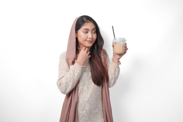 Donna musulmana asiatica assetata con il velo sulla testa e l'hijab che tiene il caffè in una tazza di plastica in attesa dell'iftar per bere il concetto del Ramadan