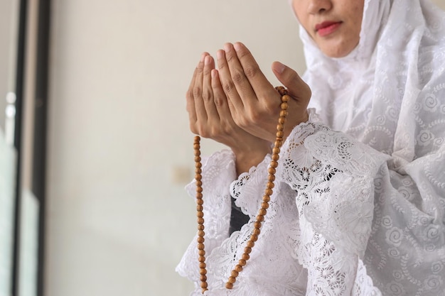 Donna musulmana asiatica che indossa abiti tradizionali hijab con rosario che prega nella moschea
