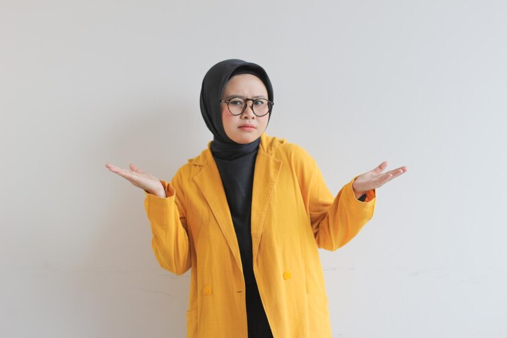 Donna musulmana asiatica che indossa un blazer che sorride sicura e felice con entrambe le mani che presentano uno spazio vuoto