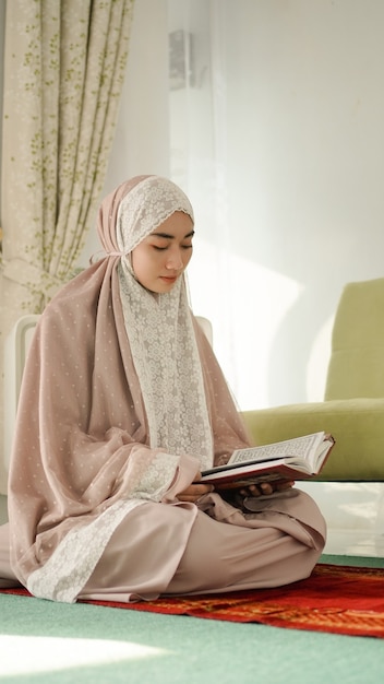 Donna musulmana asiatica che legge seriamente il corano