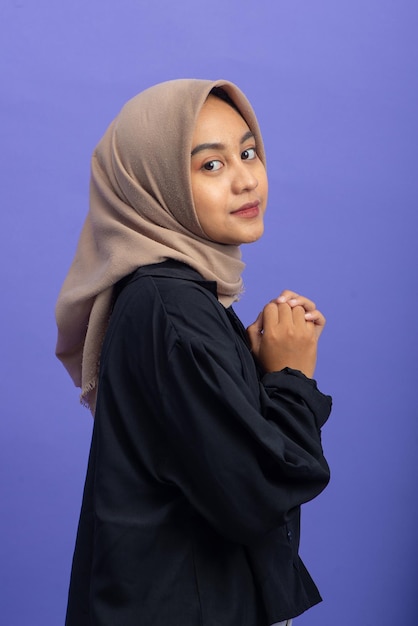 Donna musulmana asiatica con gesto attraente su sfondo viola