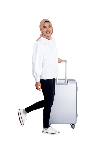 Donna musulmana asiatica in un velo che cammina con una valigia