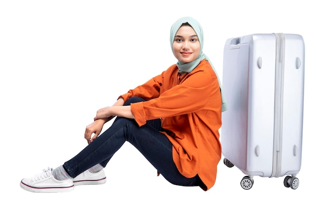 Donna musulmana asiatica in un velo seduto con una valigia