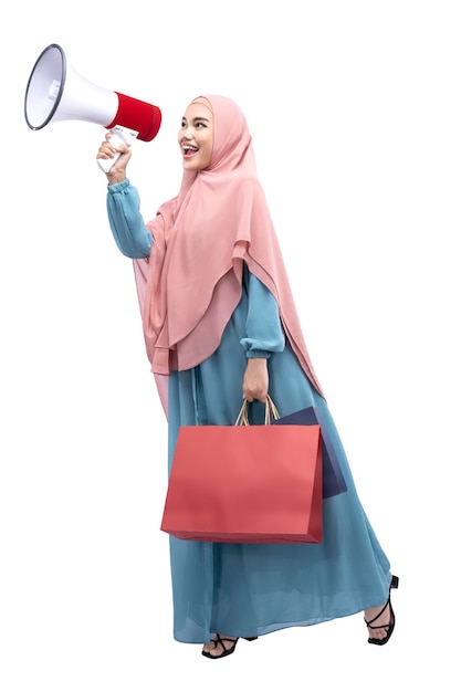 Donna musulmana asiatica in velo che tiene megafono e borse della spesa
