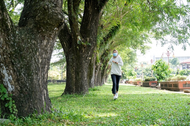 Donna musulmana che fa sport e utilizza una maschera all'aperto per prevenire la diffusione del virus