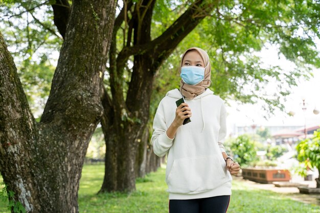 Donna musulmana che fa sport e utilizza una maschera all'aperto per prevenire la diffusione del virus