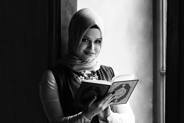 Donna musulmana che legge il libro sacro islamico Corano
