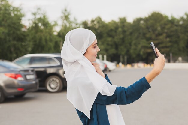 Donna musulmana che prende selfie. Felice bella ragazza con sciarpa scattare foto di se stessa utilizzando smartphone.