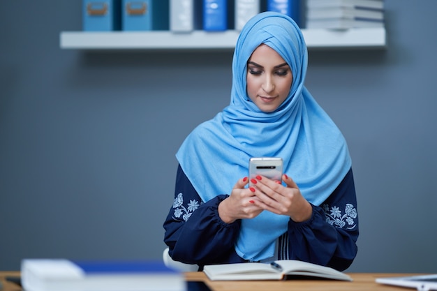 Donna musulmana che usa lo smartphone in ufficio
