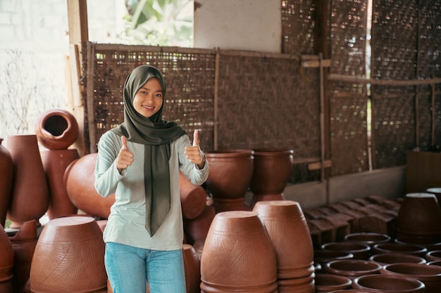 Donna musulmana con due pollici in su in piedi tra le ceramiche