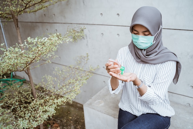 Donna musulmana con gel disinfettante per le mani