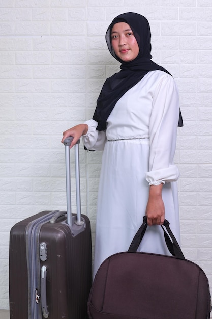 Donna musulmana con hijab tenendo la valigia isolata su sfondo bianco