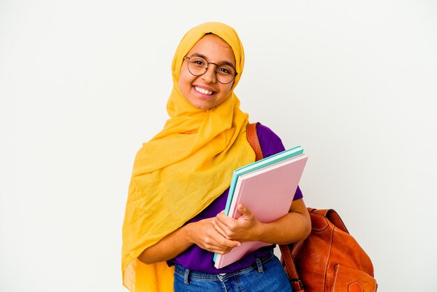 Donna musulmana del giovane studente che indossa un hijab isolato sulla parete bianca felice, sorridente e allegra.