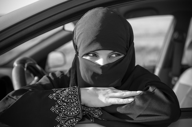 Donna musulmana in attesa in fila nel traffico. Bianco e nero