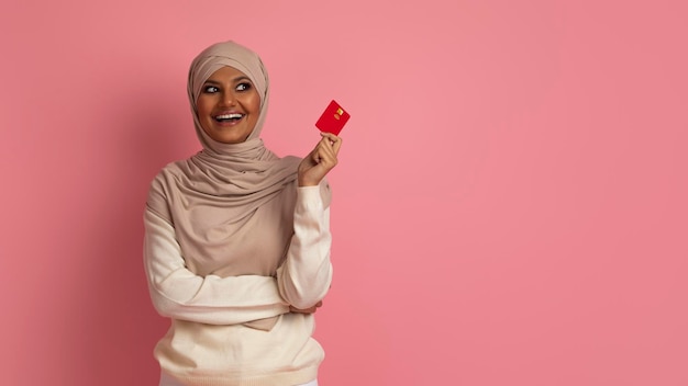 Donna Musulmana In Hijab In Possesso Di Carta Di Credito E In Posa Su Sfondo Rosa