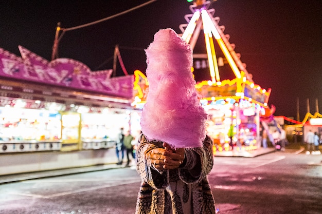 Donna nascosta con zucchero filato rosa fragola di notte luna park