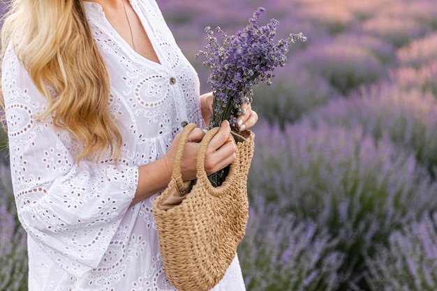 Donna nel campo di fiori di lavanda al tramonto in abito viola Francia Provenza