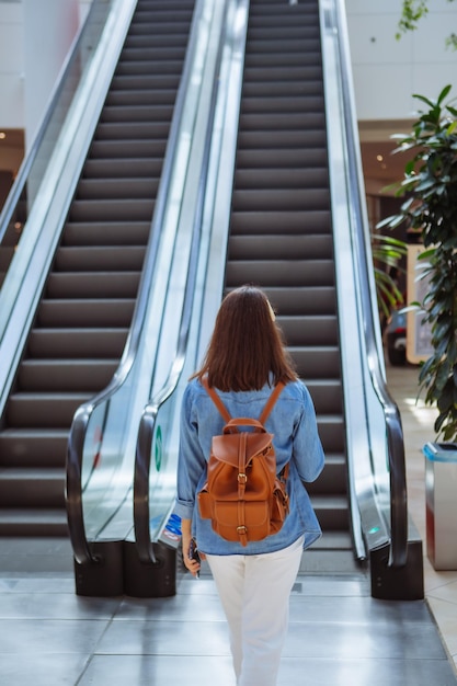 Donna nel centro commerciale della città che cammina verso la scala mobile