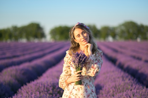 Donna nel giacimento della lavanda al tramonto che porta il vestito da estate