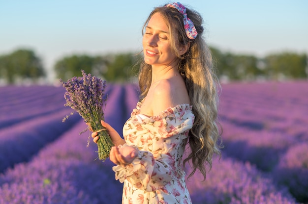 Donna nel giacimento della lavanda al tramonto che porta il vestito da estate