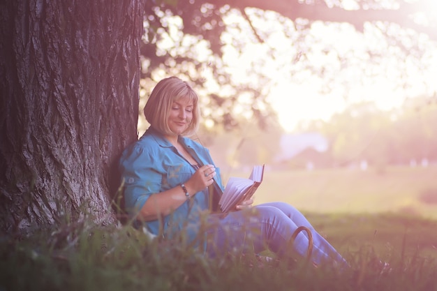 Donna nel parco al tramonto con libro