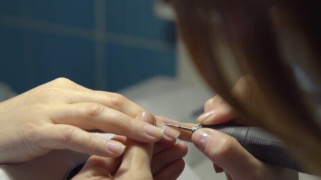 Donna nel salone, ottenendo una manicure. Lavorazione e sagomatura.