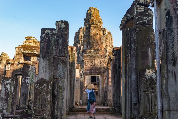 Donna nel tempio di Bayon guardando facce di pietra