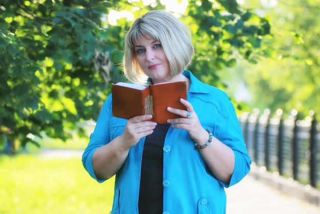 Donna nell'albero verde del parco con il libro