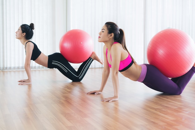 Donna nell&#39;allenamento di yoga di pratica degli abiti sportivi che allunga nella palestra all&#39;interno.