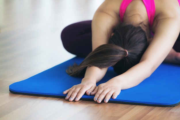 Donna nell&#39;allenamento di yoga di pratica degli abiti sportivi che allunga nella palestra all&#39;interno.