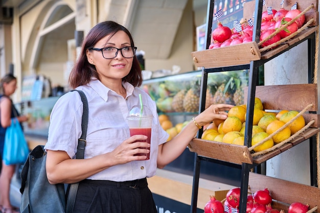 Donna nella barra all'aperto del succo di frutta con succo fresco