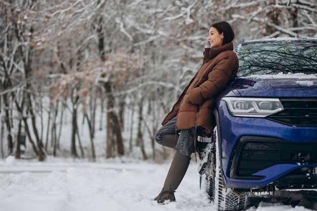 Donna nella foresta invernale con la sua auto