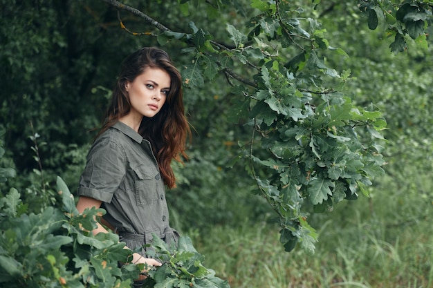 Donna nella foresta Tiene le mani in tasca con foglie verdi sullo sfondo della natura
