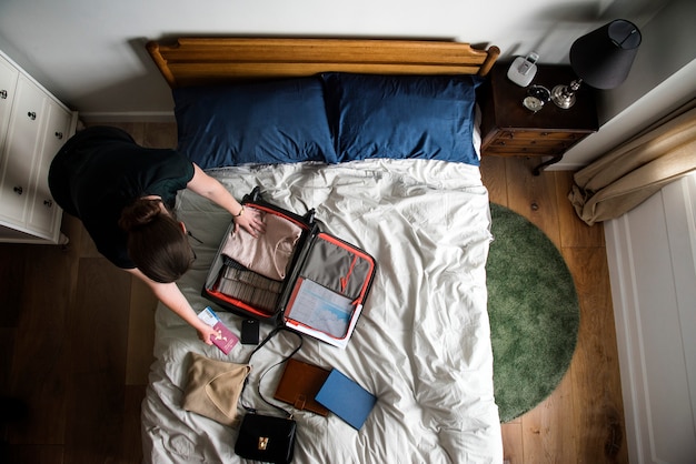 Donna nella sua camera da letto che fa i bagagli per viaggiare