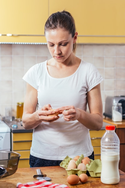 Donna nelle uova di cracking della cucina