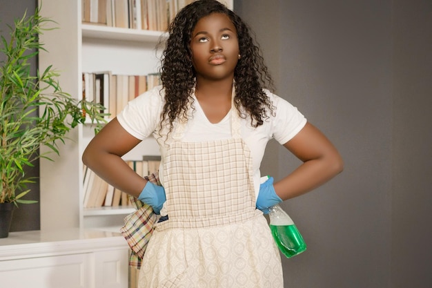 Donna nera americana con le mani sui fianchi che pianifica come fare la migliore pulizia nel suo primo piano domestico