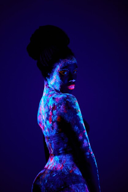 Donna nera magra con luminescenza, fluorescenza, body art isolata sul buio