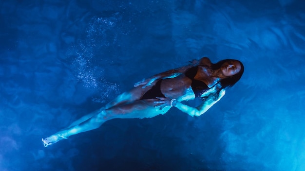 Donna nuotatrice in piscina di notte in vacanza vista dall'alto