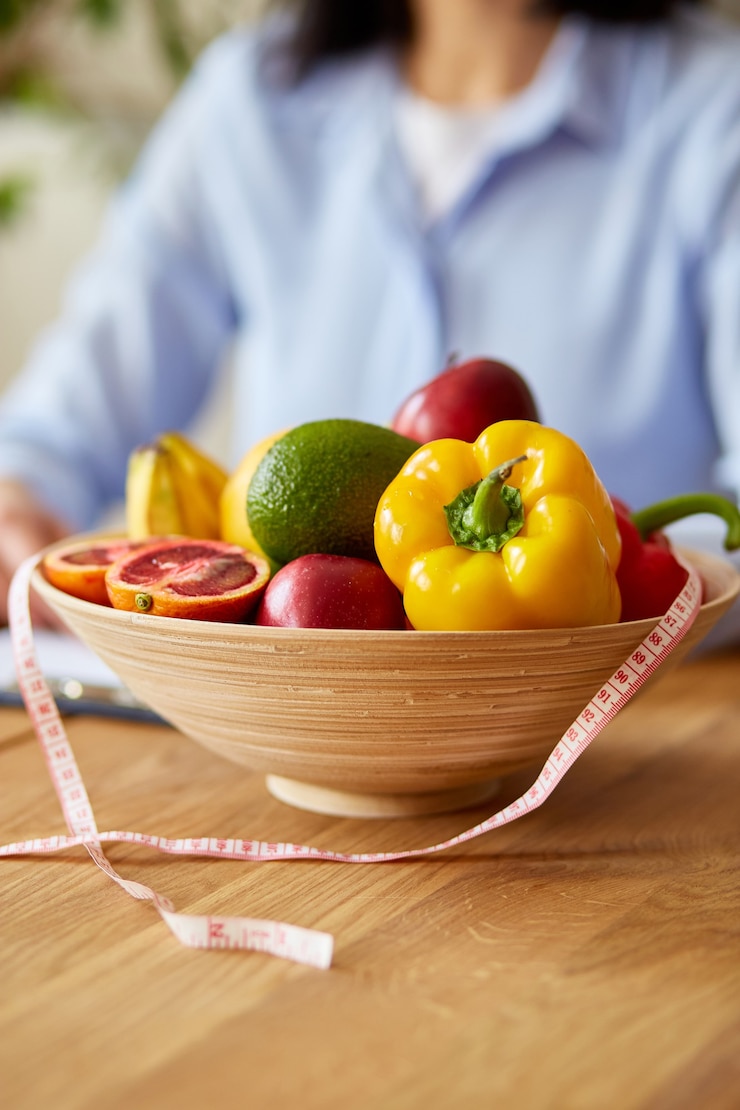 Foto donna nutrizionista che scrive un programma di dieta, con frutta e verdura sane