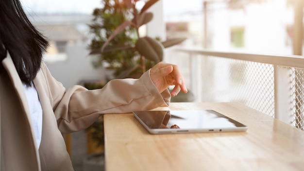 Donna o donna d'affari che lavora a distanza nella caffetteria utilizzando un tablet portatile per controllare il suo progetto