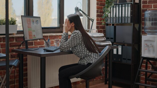 Donna oberata di lavoro che si sente stressata per la scadenza del lavoro, lavorando al computer nell'ufficio di avvio. Imprenditore frustrato con carico di lavoro e esaurimento che progetta grafici aziendali sotto pressione.