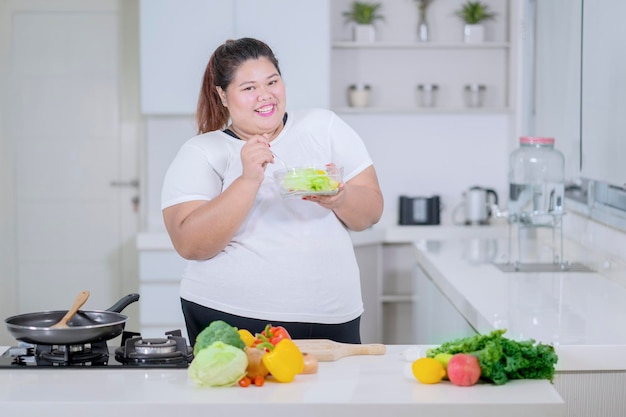 Donna obesa che assaggia una ciotola di insalata sana