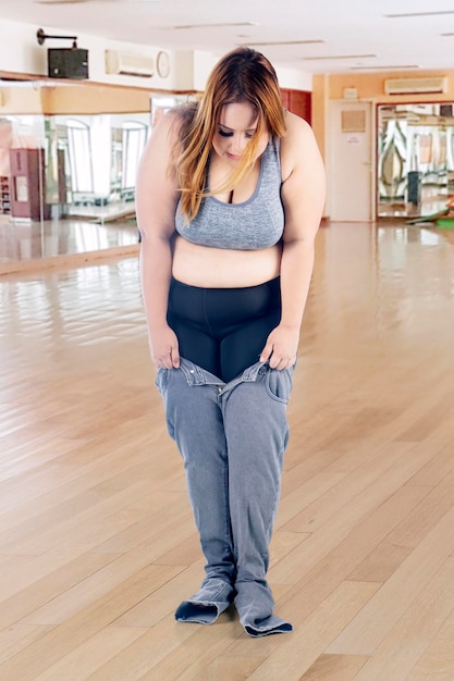 Donna obesa che cerca di indossare i suoi vecchi jeans