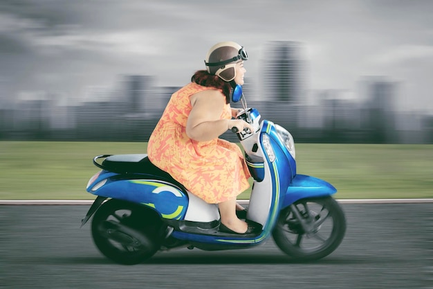 Donna obesa che guida uno scooter ad alta velocità