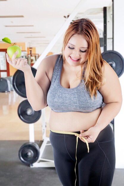 Donna obesa con nastro adesivo di misura e mela