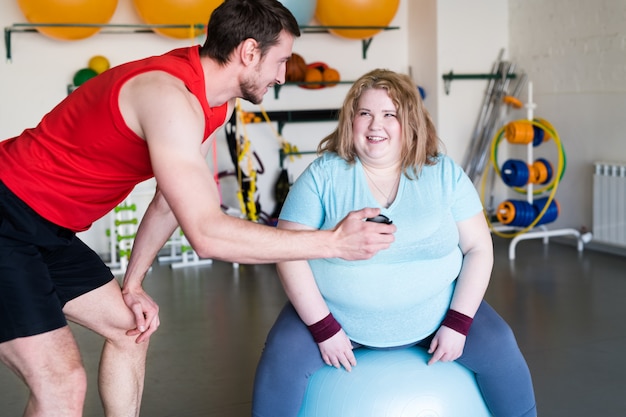 Donna obesa sorridente con istruttore