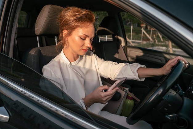 Donna occupata che utilizza il telefono cellulare alla guida dell'auto. Concetto di guida distratto