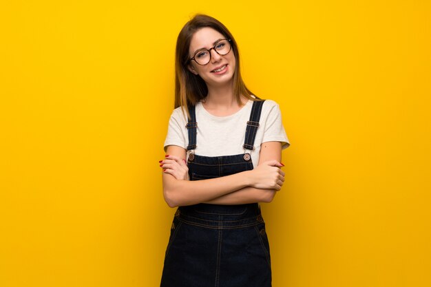 Donna oltre muro giallo con occhiali e felice