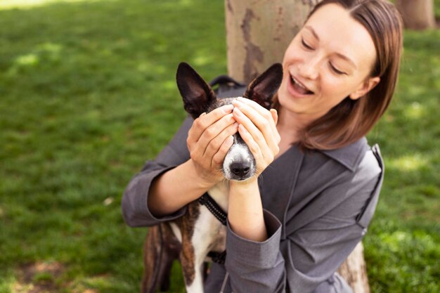 Donna ottimista in abito grigio sorridente e giocando con il cane.