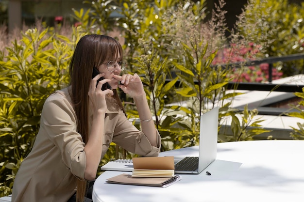 Donna parlando al telefono con il computer portatile